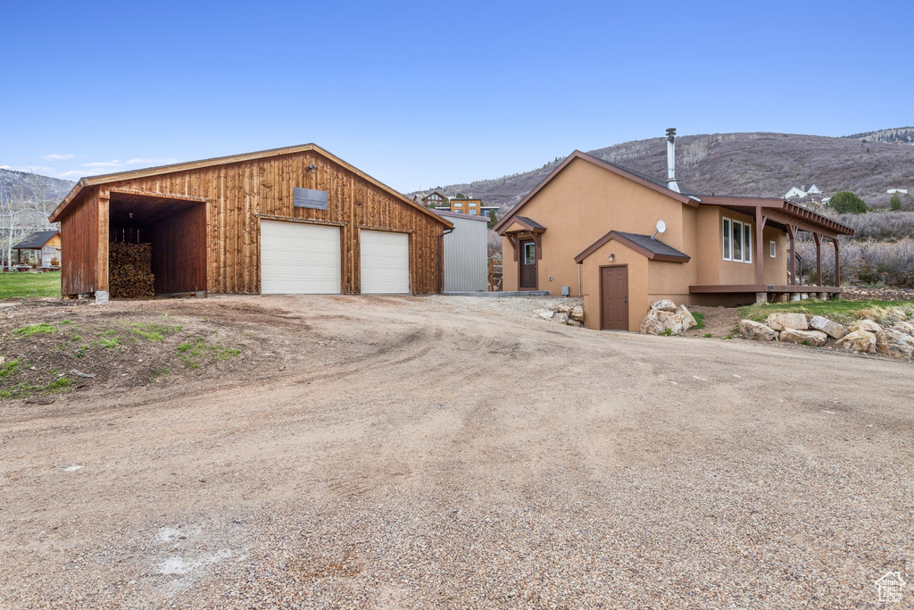 Single story home with a detached garage, a mountain view, stucco siding, and an outbuilding