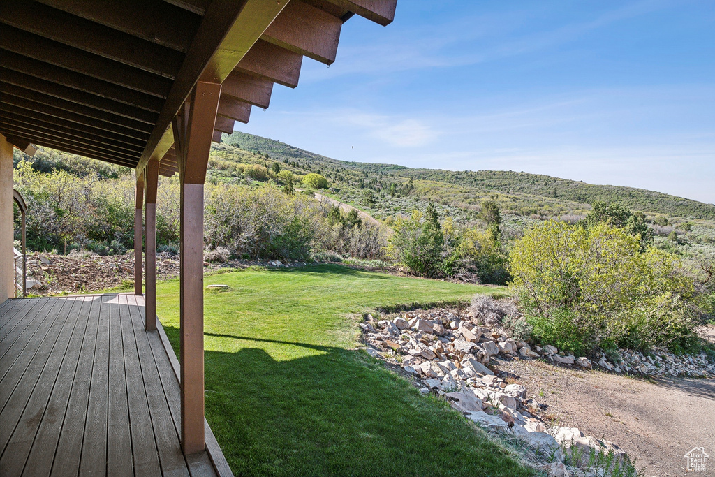 View of grassy yard featuring a deck with mountain view