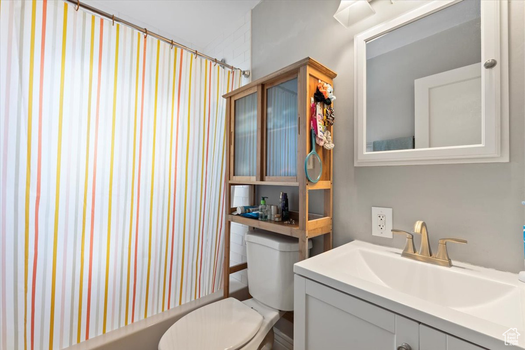 Full bathroom with shower / bathtub combination with curtain, toilet, and vanity