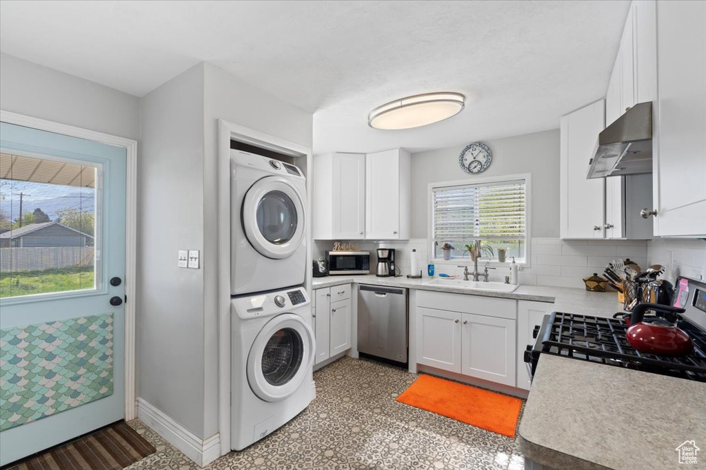 Laundry room featuring a sink, stacked washer and clothes dryer, laundry area, and baseboards