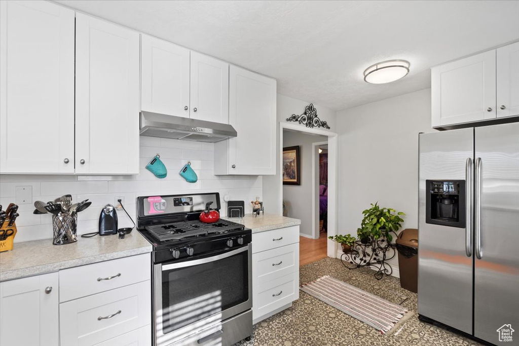 Kitchen featuring under cabinet range hood, tasteful backsplash, appliances with stainless steel finishes, and white cabinets