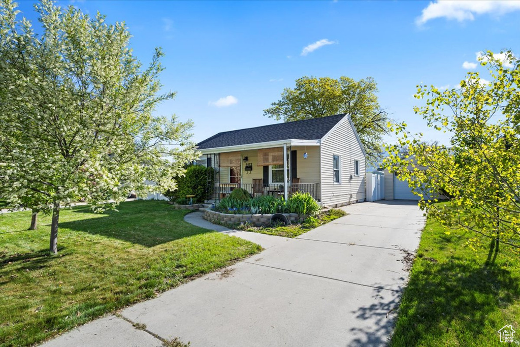 Bungalow-style house with a porch, a front lawn, and driveway