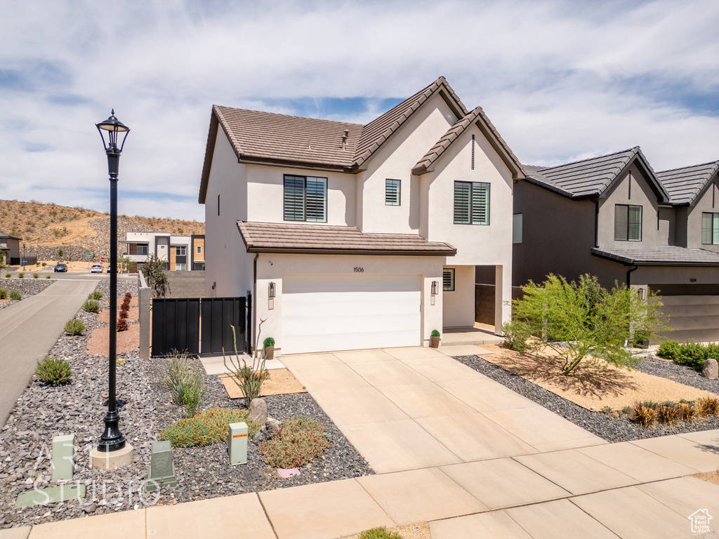 View of front of property featuring stucco siding, fence, driveway, and a garage