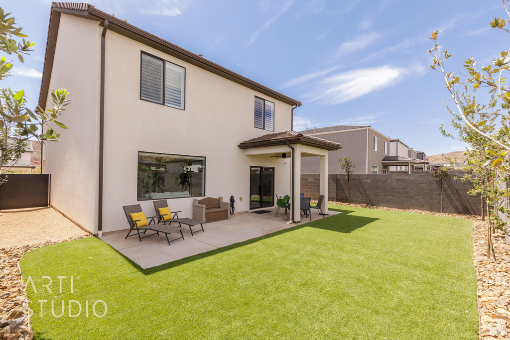 Rear view of property with a patio, a yard, stucco siding, and a fenced backyard
