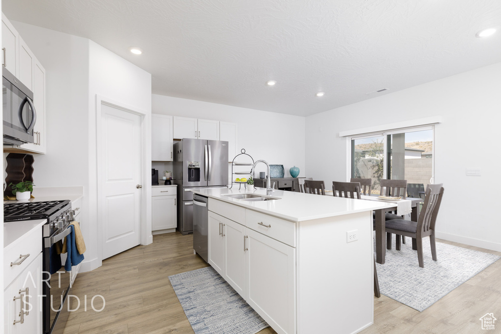 Kitchen featuring a sink, white cabinets, light wood-style flooring, and stainless steel appliances