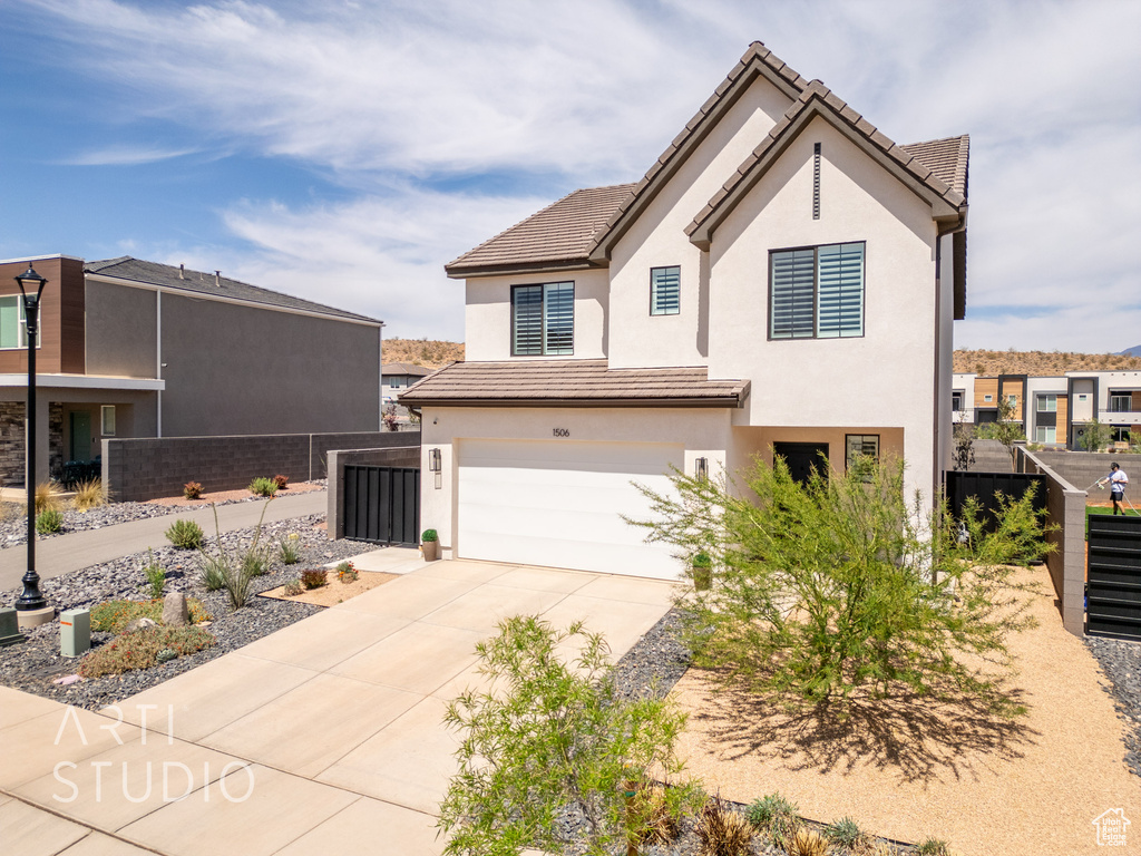 View of front of home with stucco siding, fence, a tile roof, concrete driveway, and an attached garage