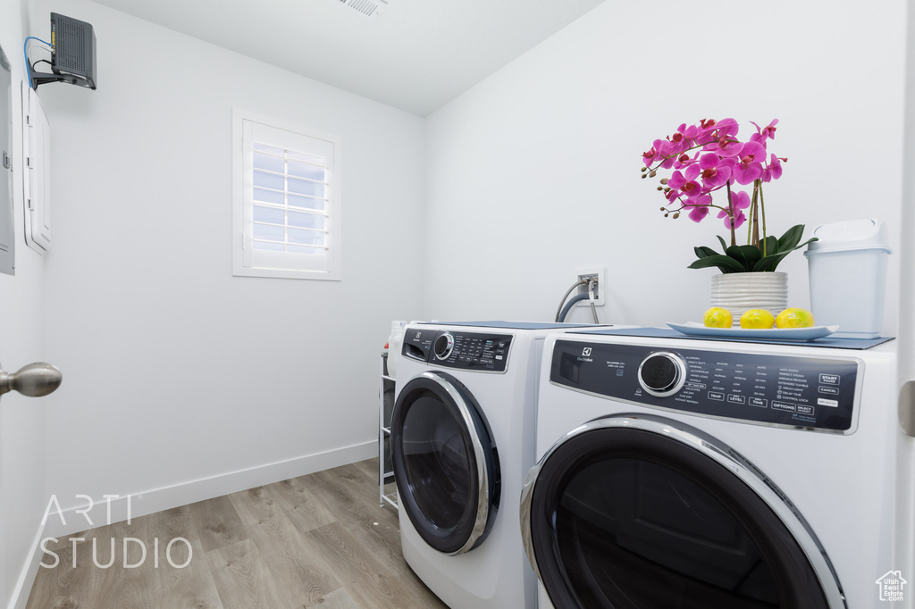 Clothes washing area with light wood finished floors, independent washer and dryer, laundry area, and baseboards