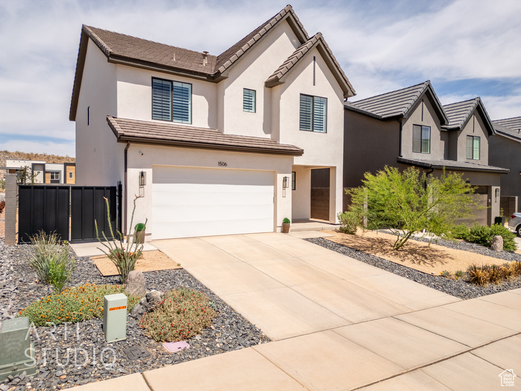 View of front of house with stucco siding, fence, driveway, and a garage