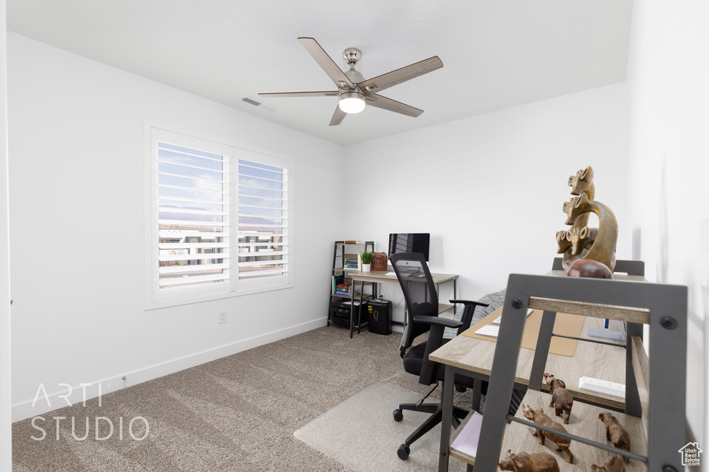 Carpeted home office with baseboards, visible vents, and ceiling fan