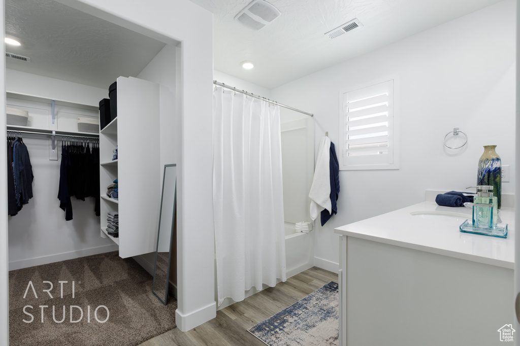 Full bathroom with baseboards, visible vents, wood finished floors, and a spacious closet