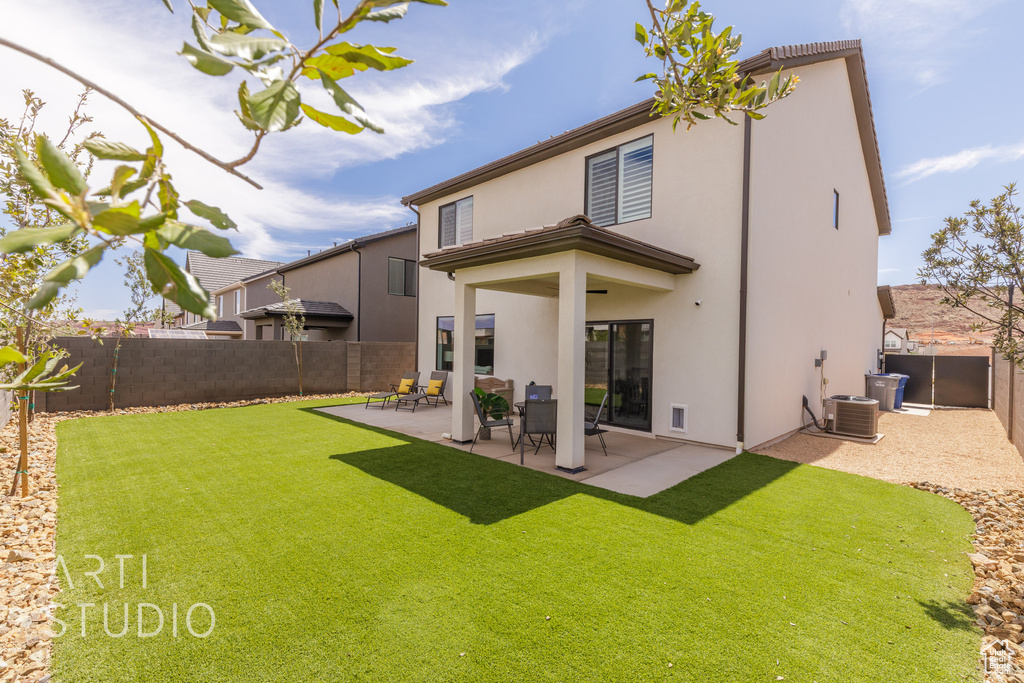 Back of property with stucco siding, a patio area, a yard, and a fenced backyard