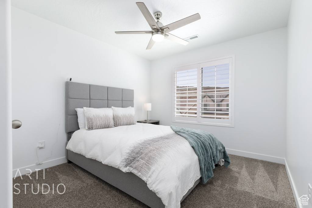 Carpeted bedroom featuring visible vents, a ceiling fan, and baseboards