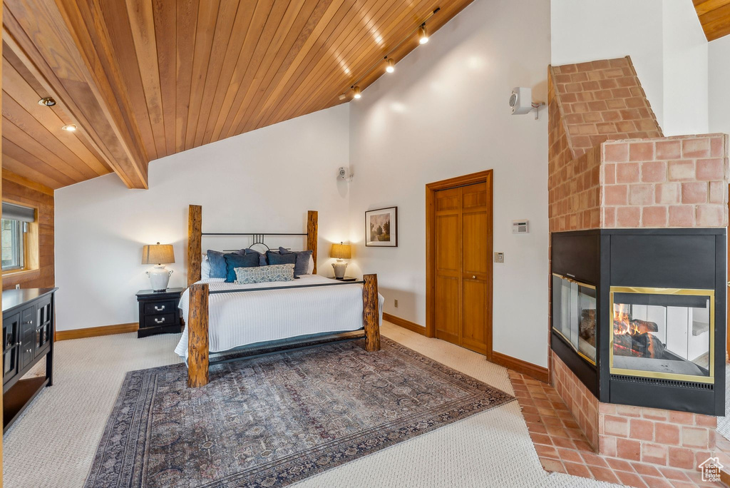 Bedroom with lofted ceiling, wood ceiling, carpet flooring, and a brick fireplace