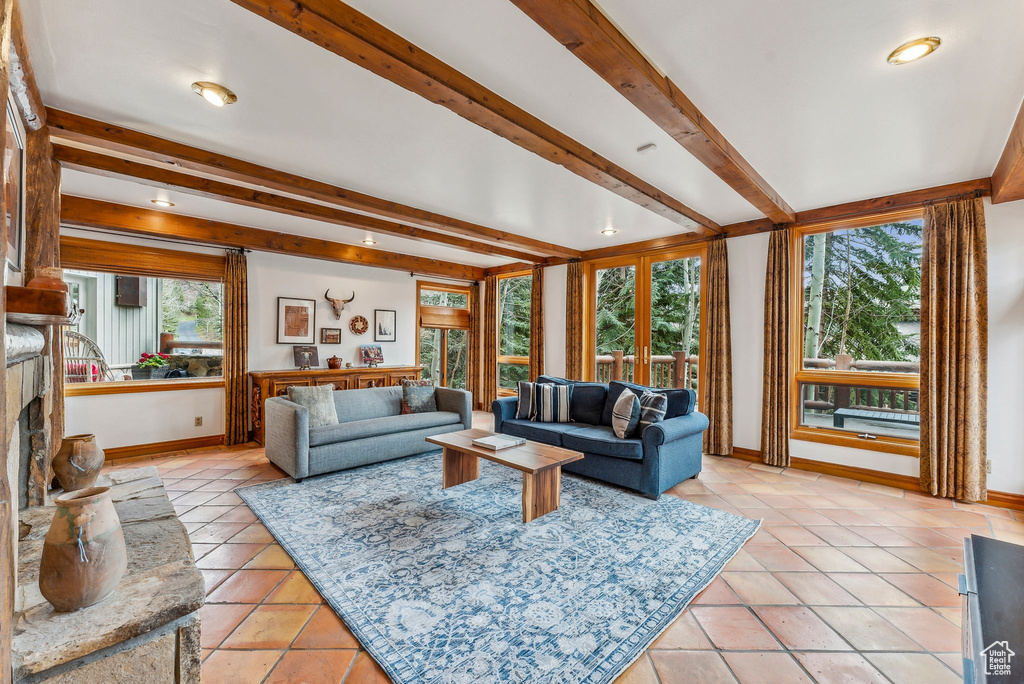 Living area with baseboards, beamed ceiling, and light tile patterned flooring