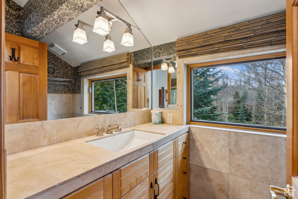 Bathroom with tasteful backsplash, vaulted ceiling, and vanity