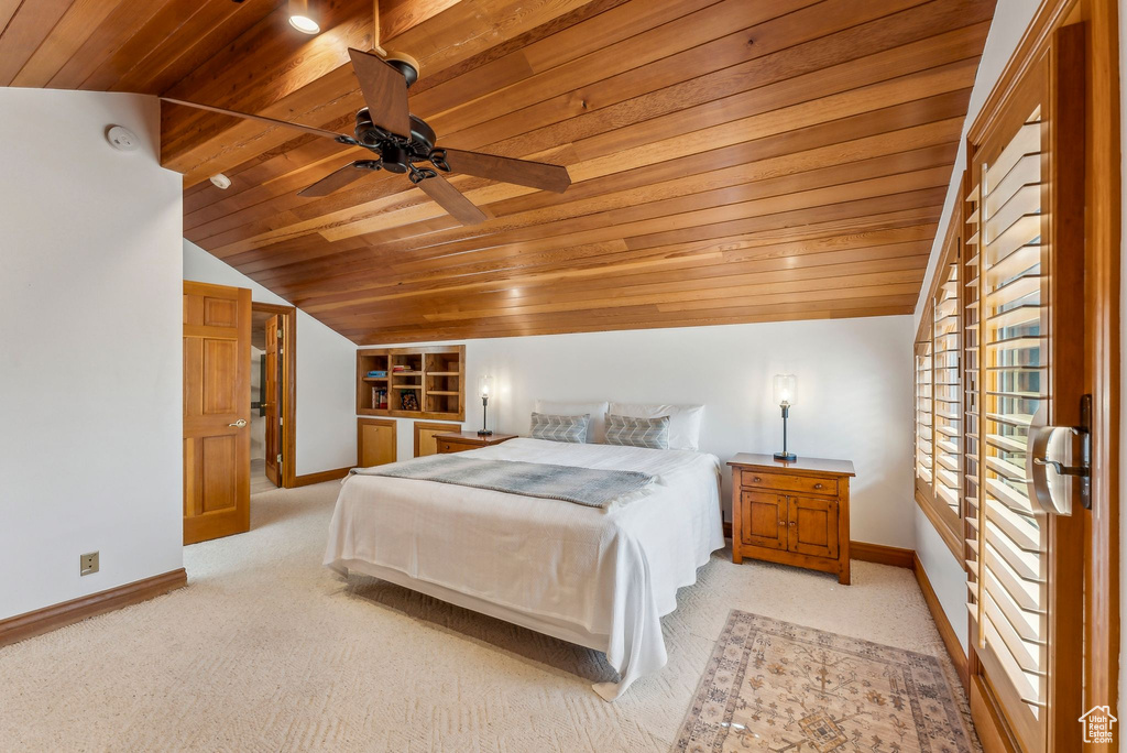 Bedroom featuring baseboards, wooden ceiling, light carpet, and vaulted ceiling