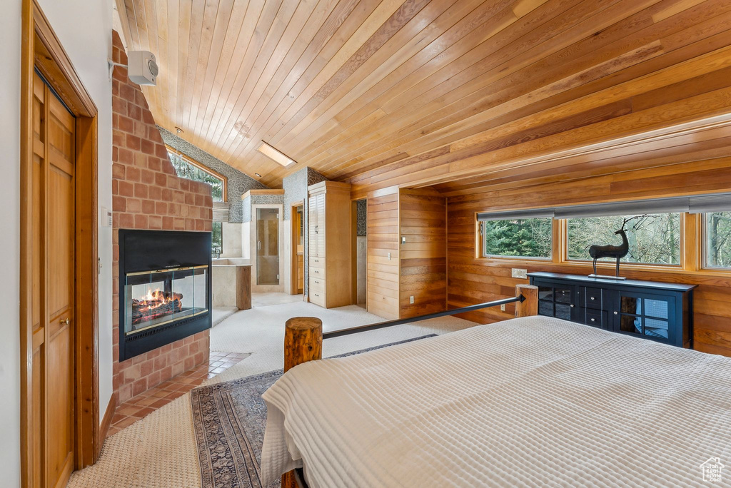 Carpeted bedroom featuring a multi sided fireplace, wood walls, lofted ceiling, and wood ceiling
