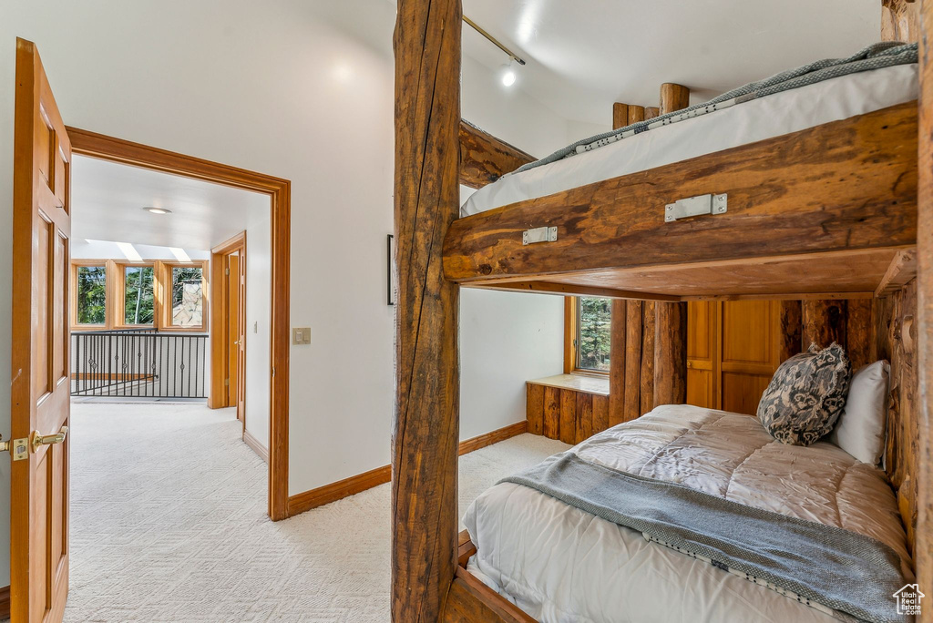 Bedroom with baseboards, light carpet, and a high ceiling