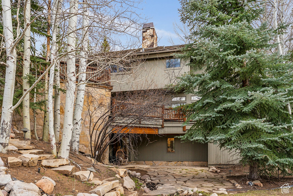 View of side of home featuring a balcony and a chimney