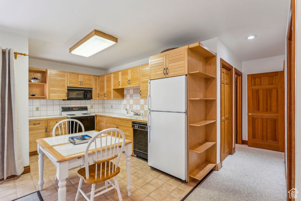 Kitchen featuring black appliances, a sink, open shelves, and decorative backsplash