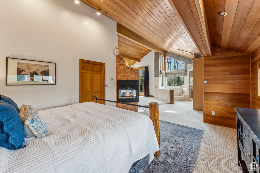Carpeted bedroom featuring wooden ceiling, a fireplace, wooden walls, and lofted ceiling
