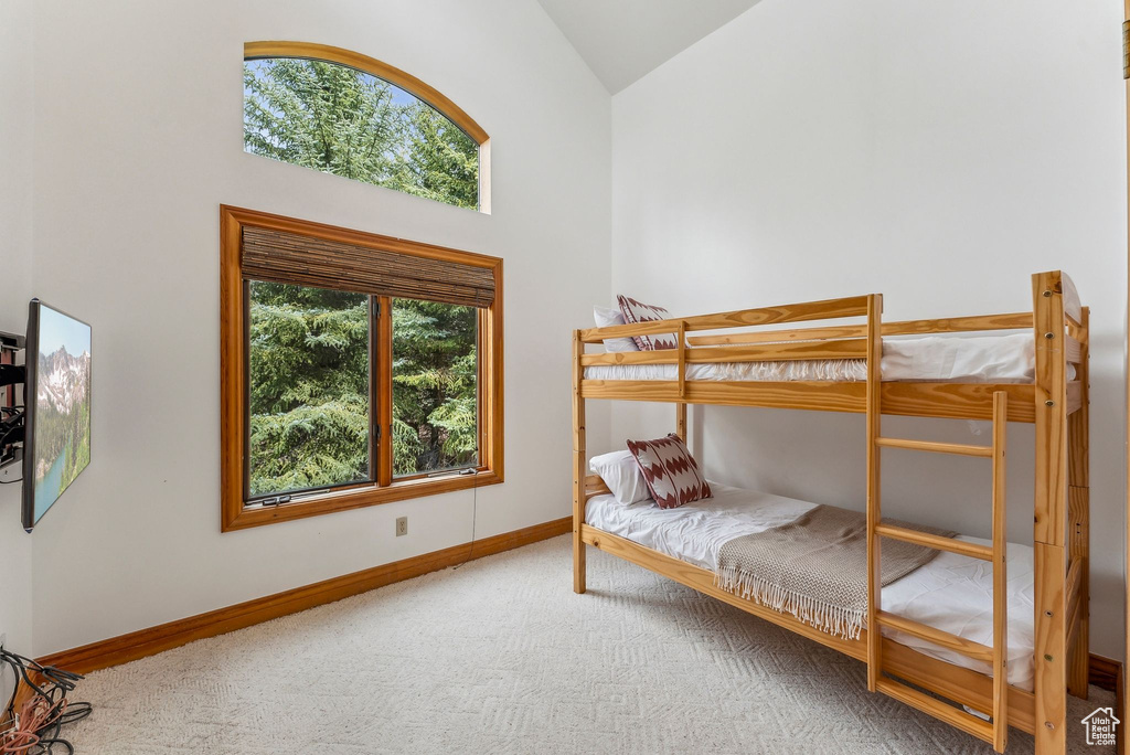 Carpeted bedroom featuring baseboards and high vaulted ceiling