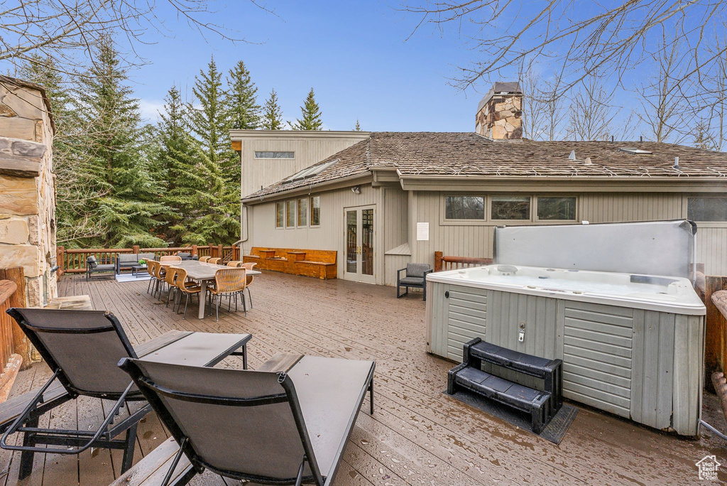 Rear view of house with a deck, a chimney, french doors, and a hot tub
