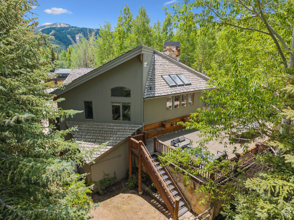 Rear view of house featuring a chimney, stairway, and a mountain view