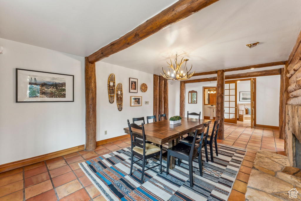 Dining room featuring an inviting chandelier, light tile patterned floors, beamed ceiling, and baseboards