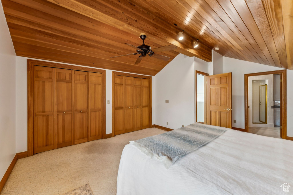 Bedroom with baseboards, wood ceiling, light colored carpet, and vaulted ceiling