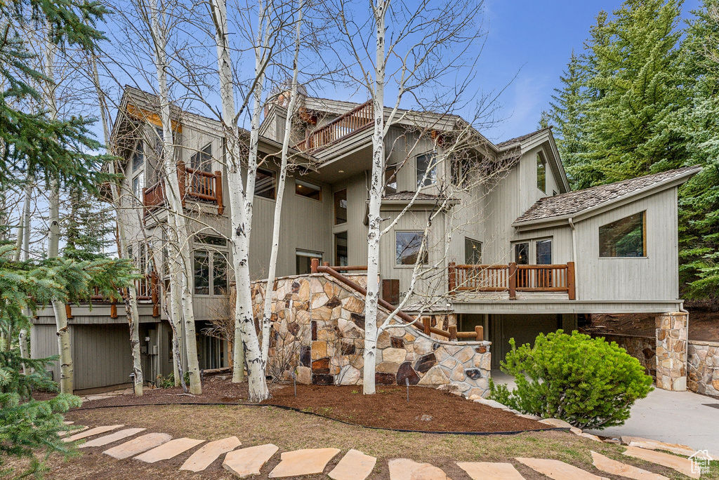 Rear view of property with stairway, a balcony, and a wooden deck