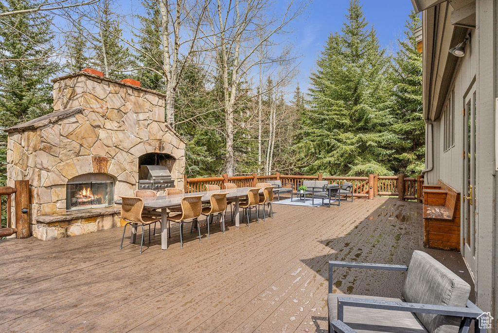 Wooden deck featuring outdoor dining space and an outdoor stone fireplace