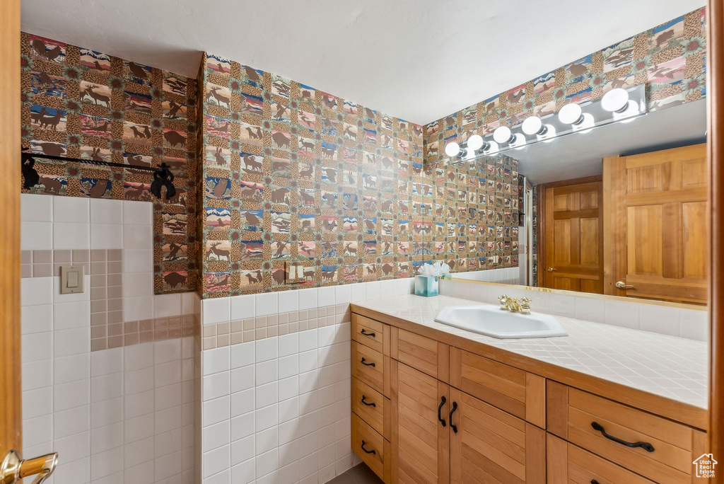Bathroom with wallpapered walls, wainscoting, and vanity