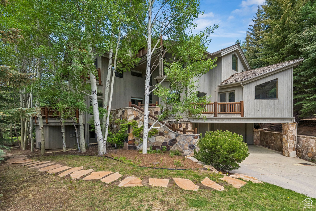 View of front of house featuring concrete driveway, a carport, and stone siding