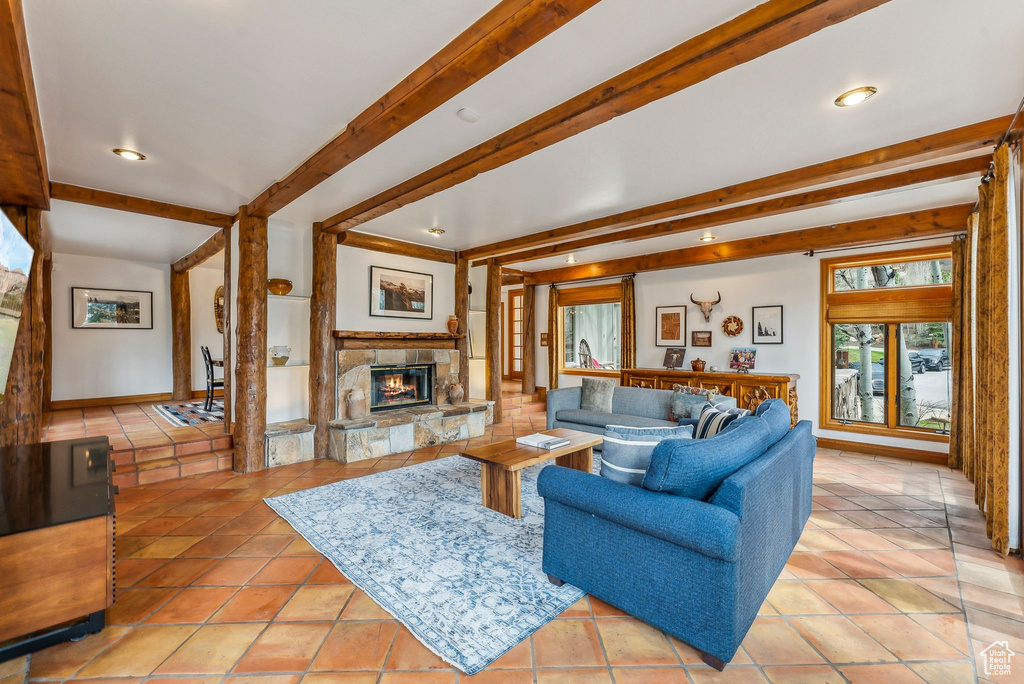 Living area with light tile patterned floors, beamed ceiling, a stone fireplace, and recessed lighting