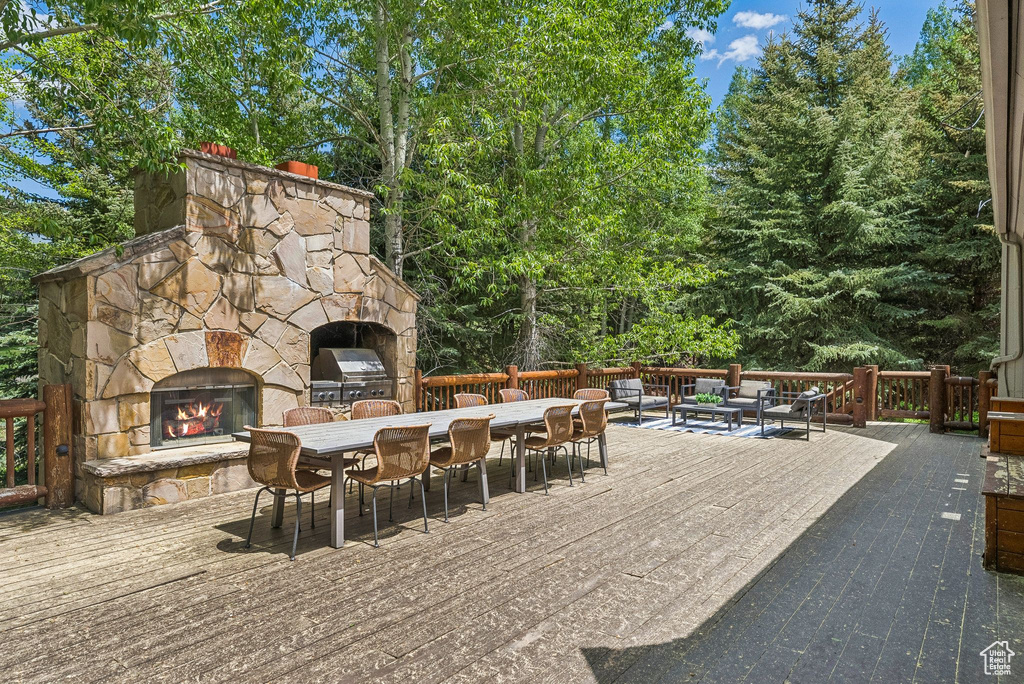 View of patio with an outdoor stone fireplace, outdoor dining area, a deck, and area for grilling