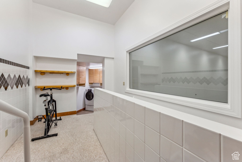 Hall with tile walls, carpet flooring, washer / dryer, and baseboards