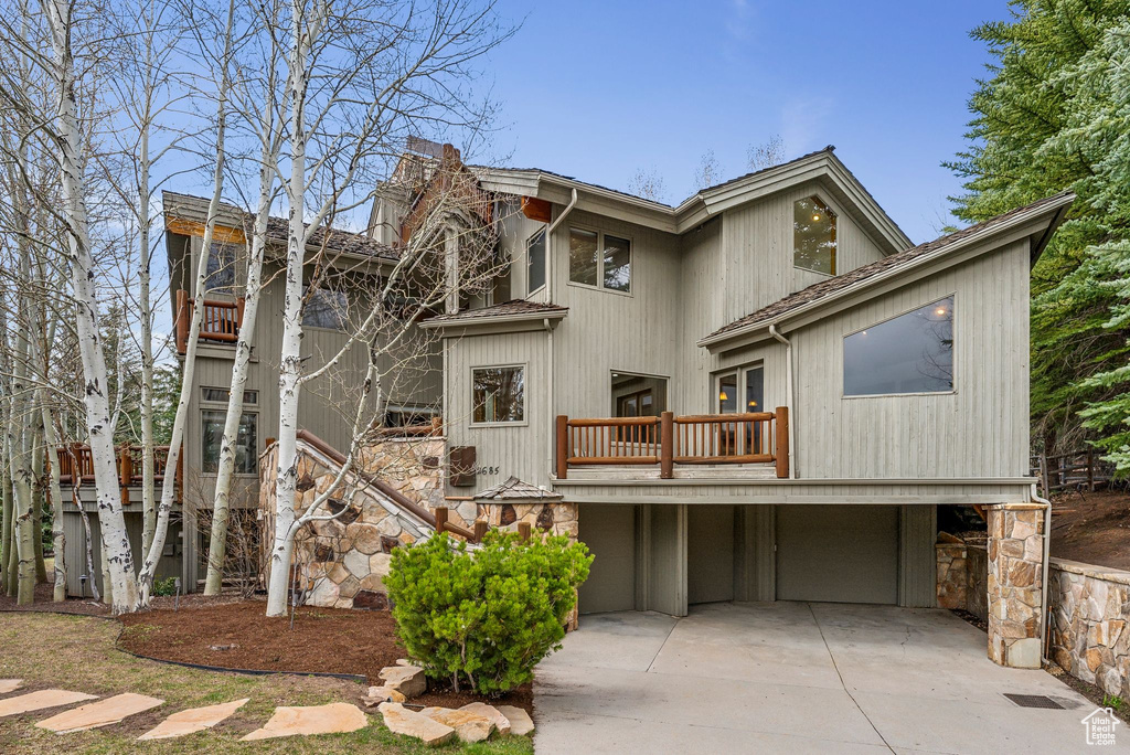 View of front of house with concrete driveway, a balcony, and an attached garage
