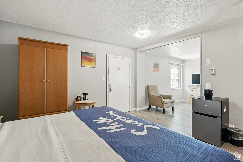 Bedroom with baseboards, light wood-style floors, and a textured ceiling