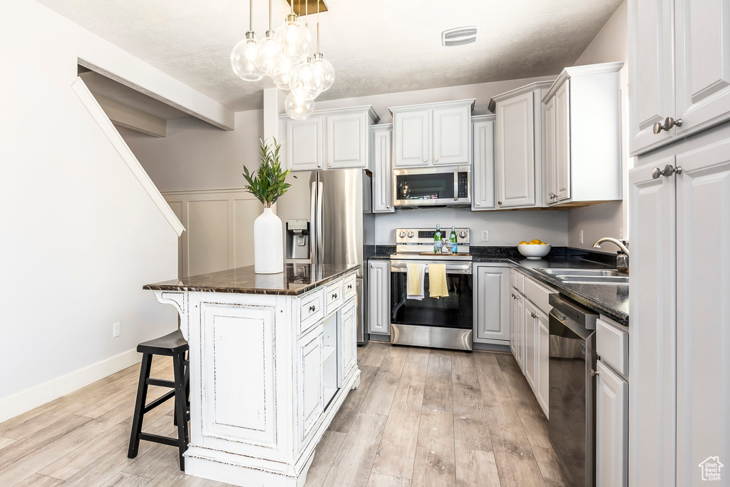 Kitchen with a sink, a breakfast bar area, light wood-style flooring, a center island, and stainless steel appliances