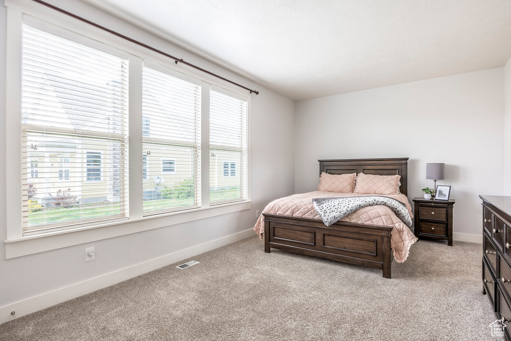 Bedroom with baseboards, visible vents, and light carpet