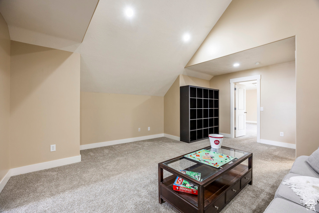 Carpeted living area with baseboards, recessed lighting, and lofted ceiling