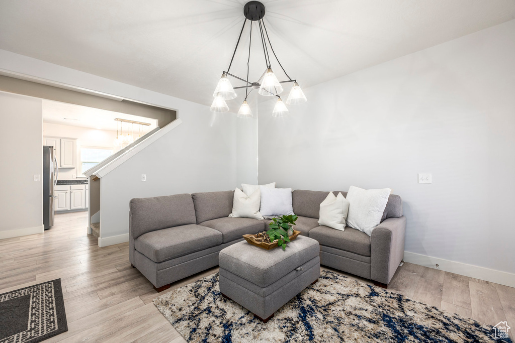 Living area featuring baseboards, light wood-style flooring, and a chandelier