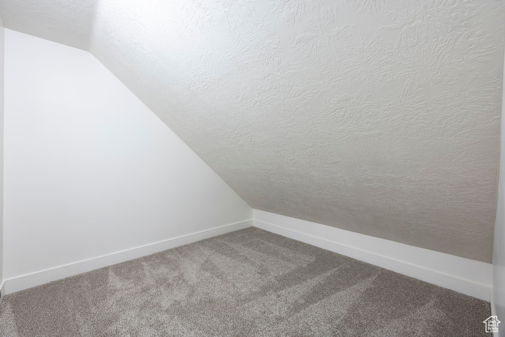 Bonus room featuring baseboards, carpet, vaulted ceiling, and a textured ceiling