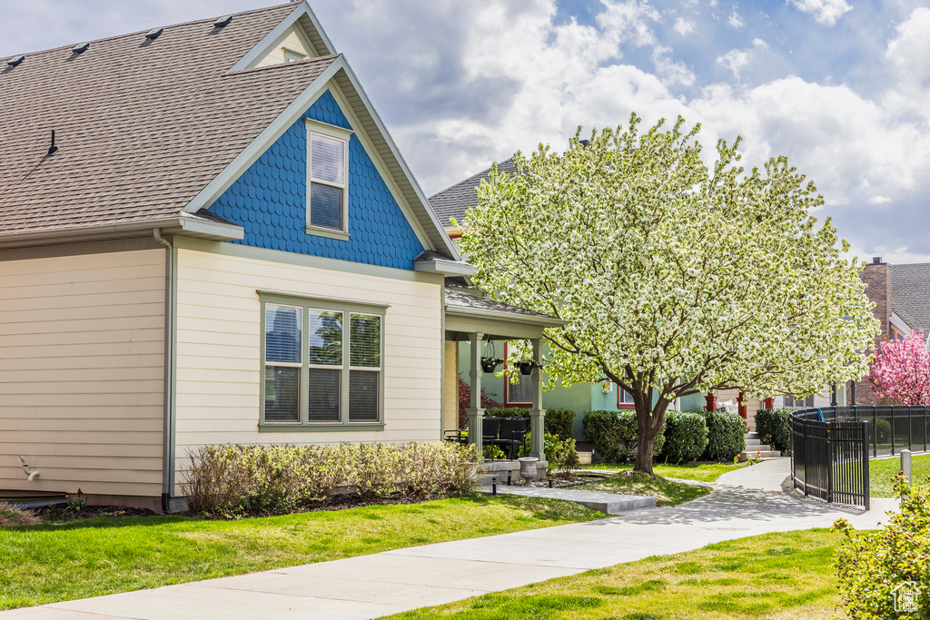 View of front of home featuring a front lawn, roof with shingles, and fence