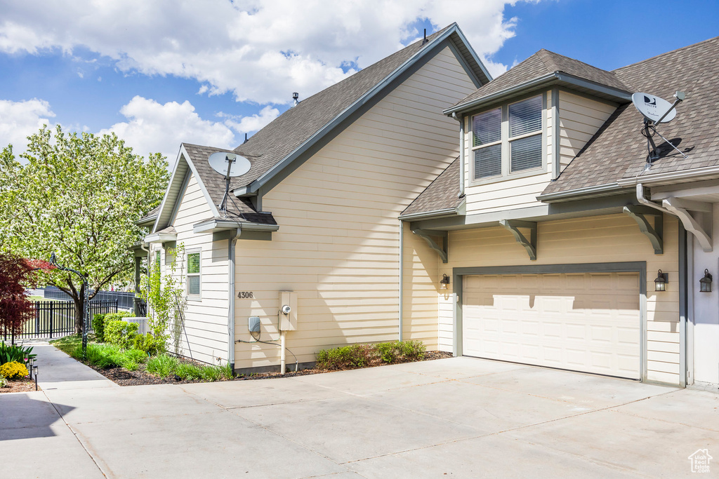 View of side of home with concrete driveway and roof with shingles