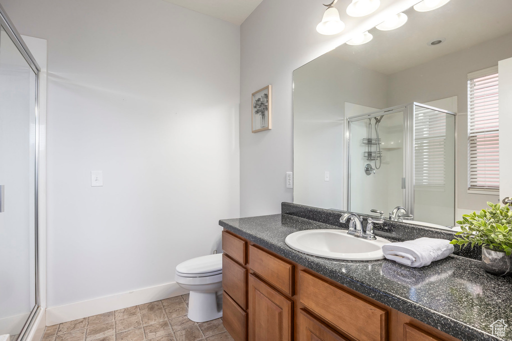Bathroom with toilet, baseboards, a shower stall, and vanity