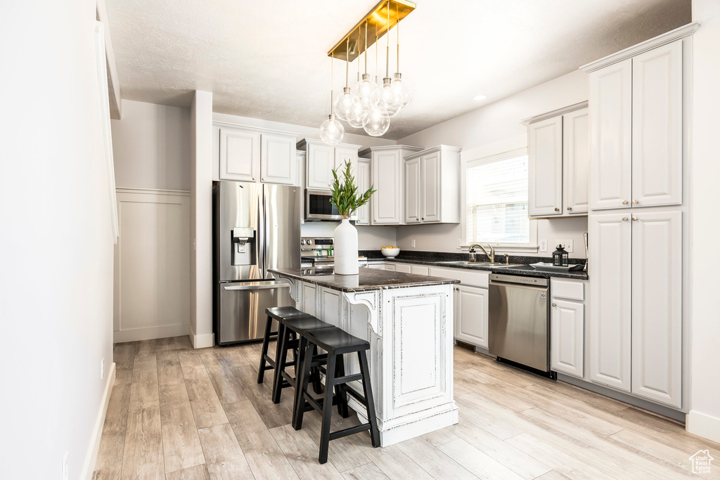Kitchen featuring appliances with stainless steel finishes, a kitchen breakfast bar, a center island, and light wood-type flooring