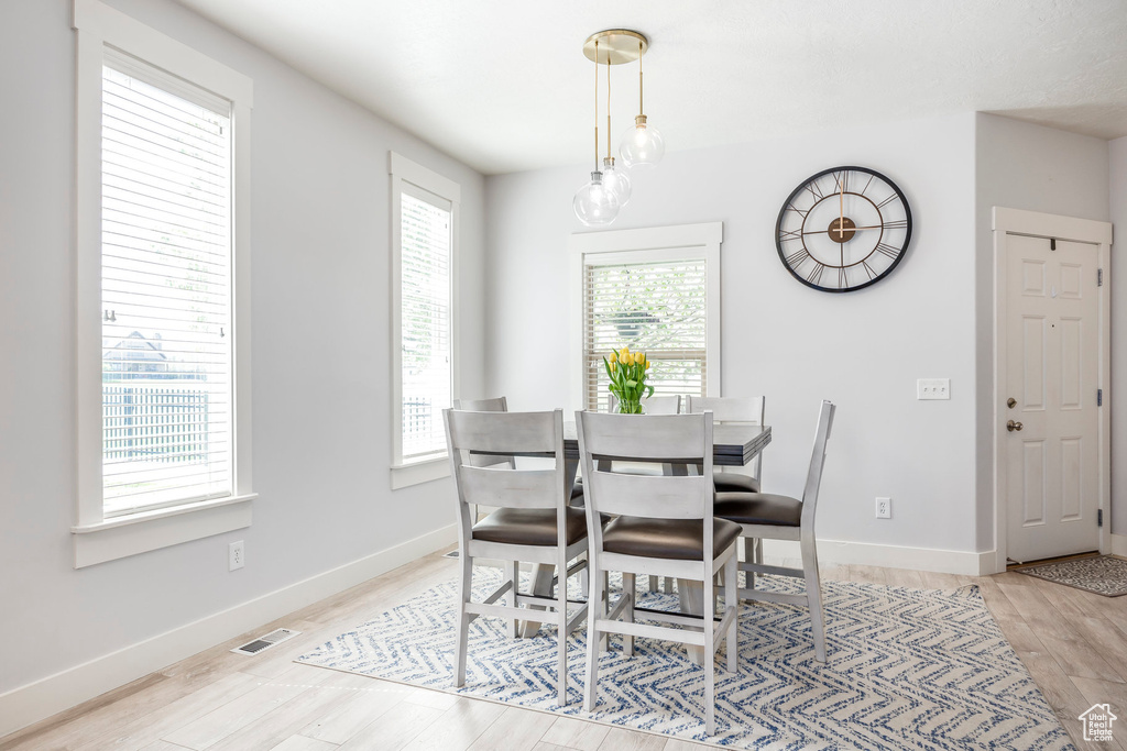 Dining space featuring light wood-style floors, baseboards, and visible vents