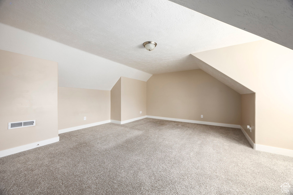 Bonus room featuring visible vents, baseboards, carpet floors, and lofted ceiling